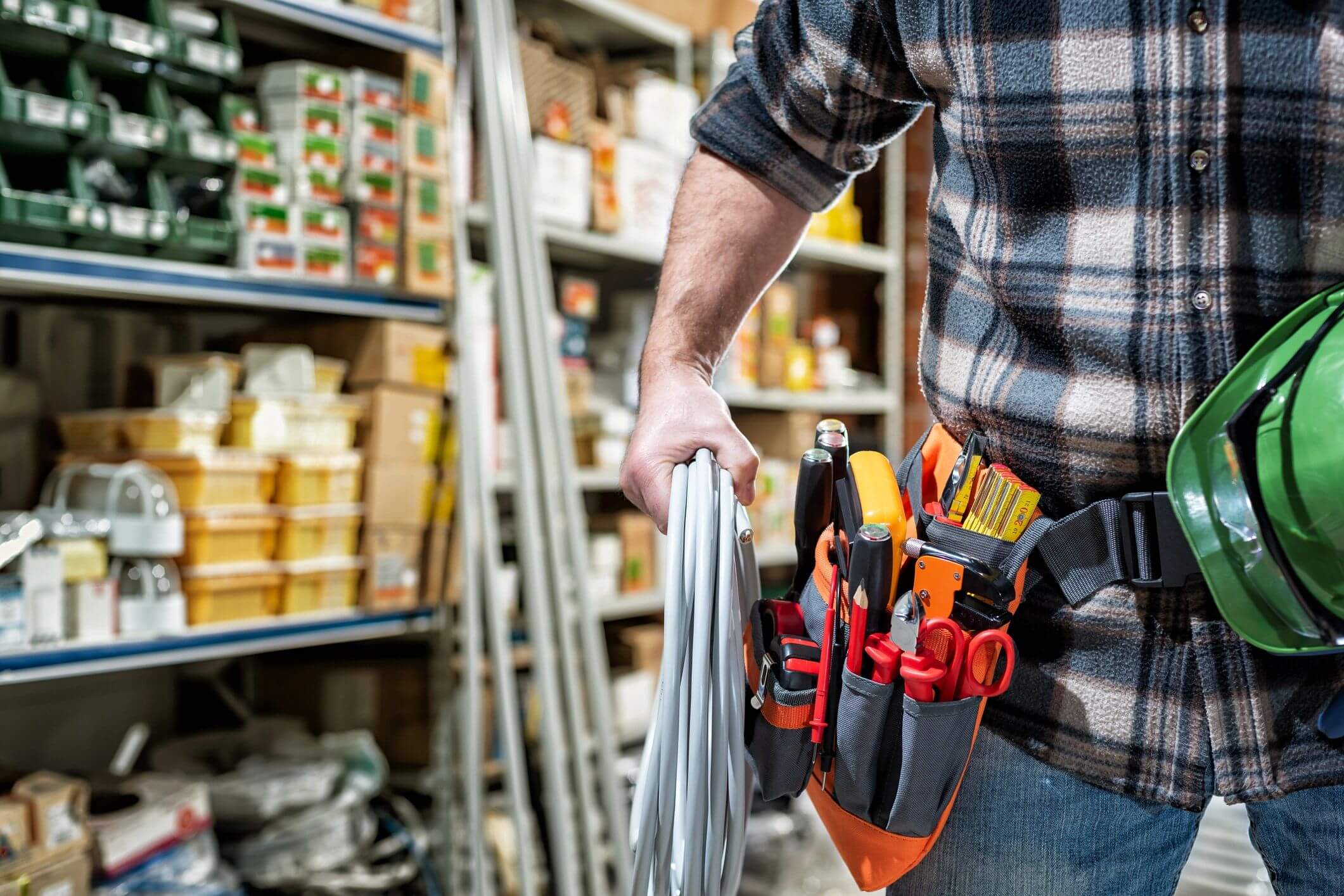 A handyman holding a coil of wire in a workshop.