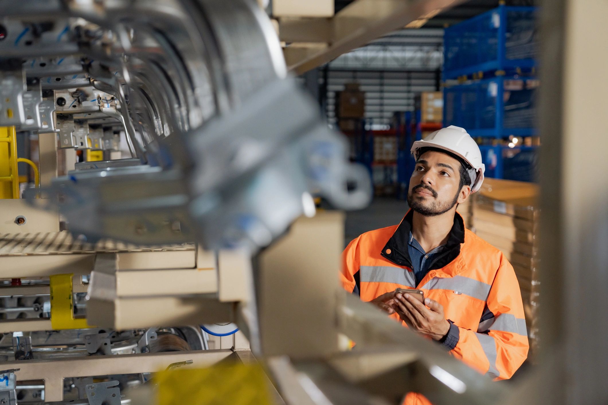 Engineer in safety gear inspecting industrial equipment in a factory.