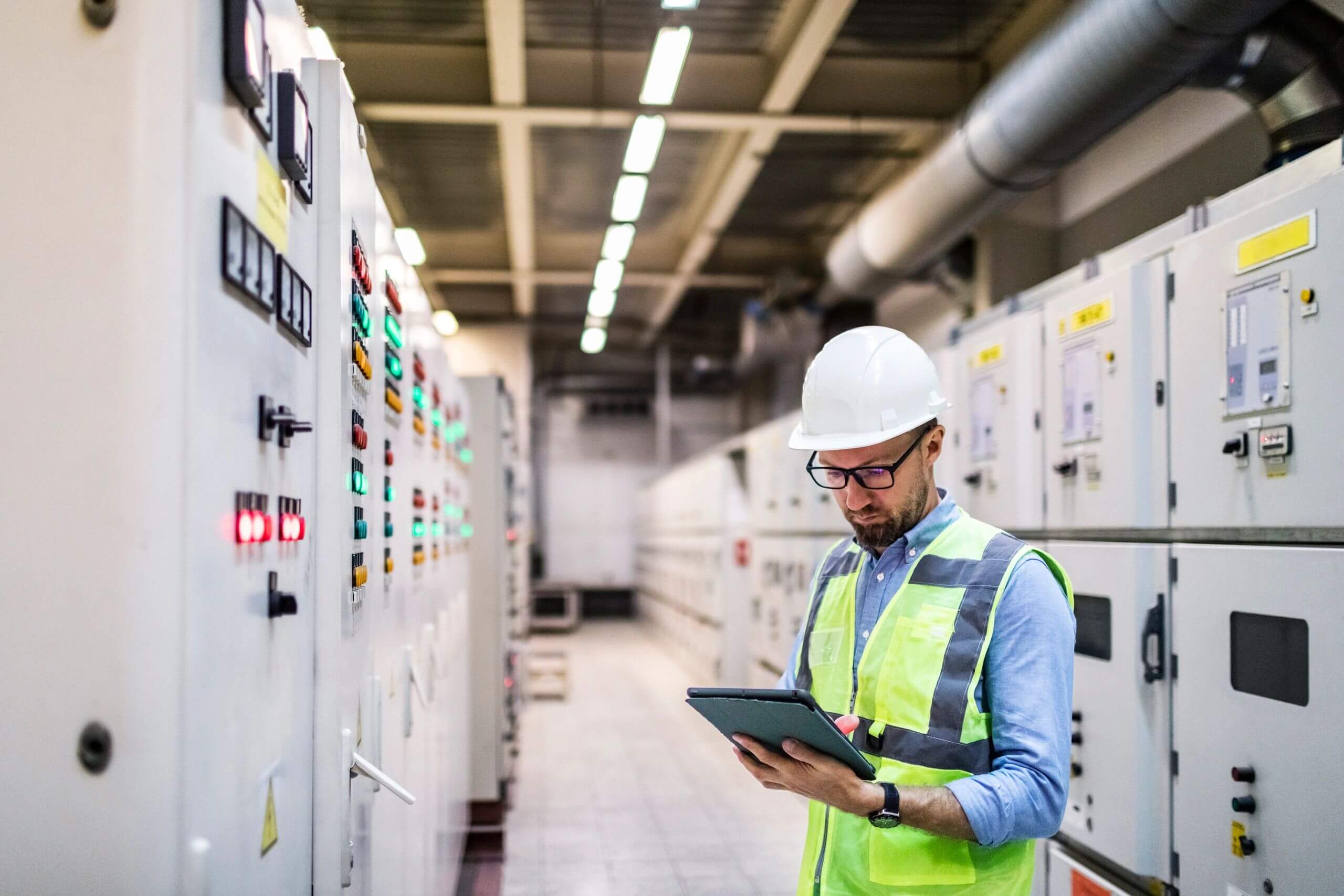 Engineer in safety gear inspecting control panels in an industrial facility.