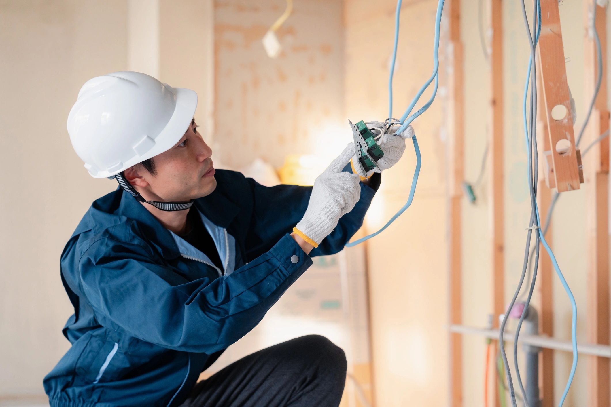 Electrician installing wiring inside a building under construction.