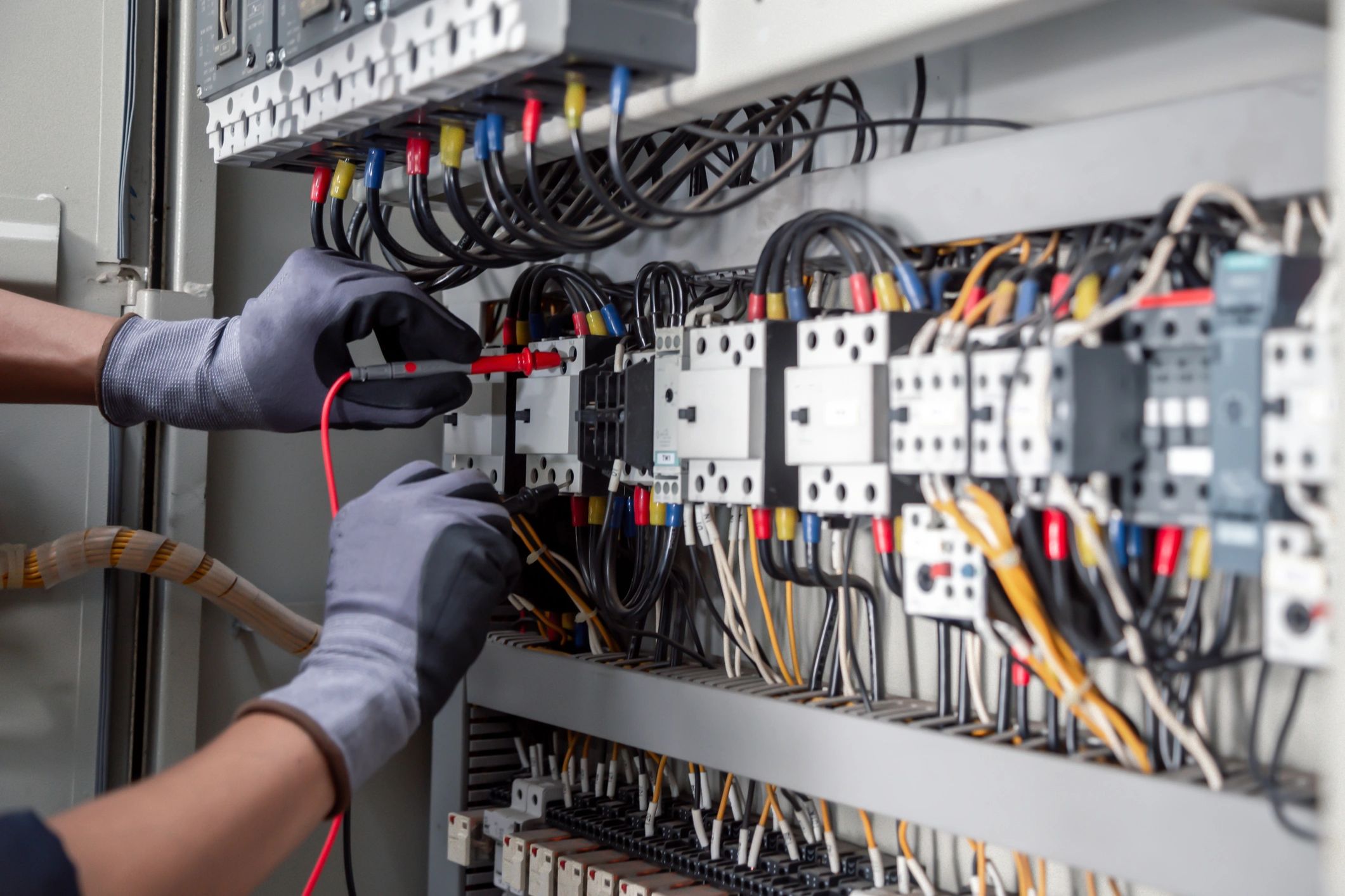 Electrician working on complex electrical wiring in control panel.